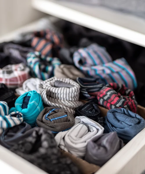 A drawer of neatly rolled socks in assorted colours and patterns