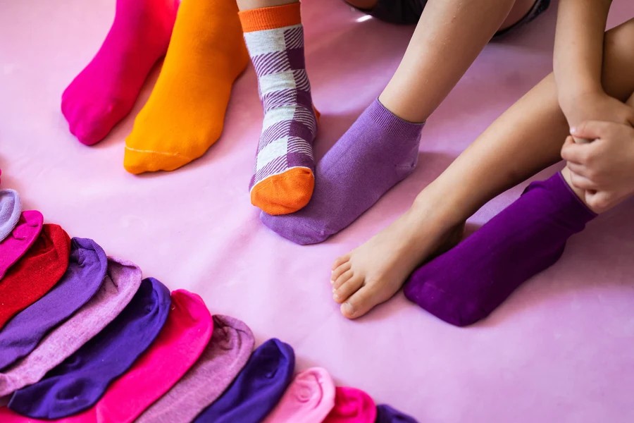 Children's feet in brightly coloured socks beside a row of folded pairs
