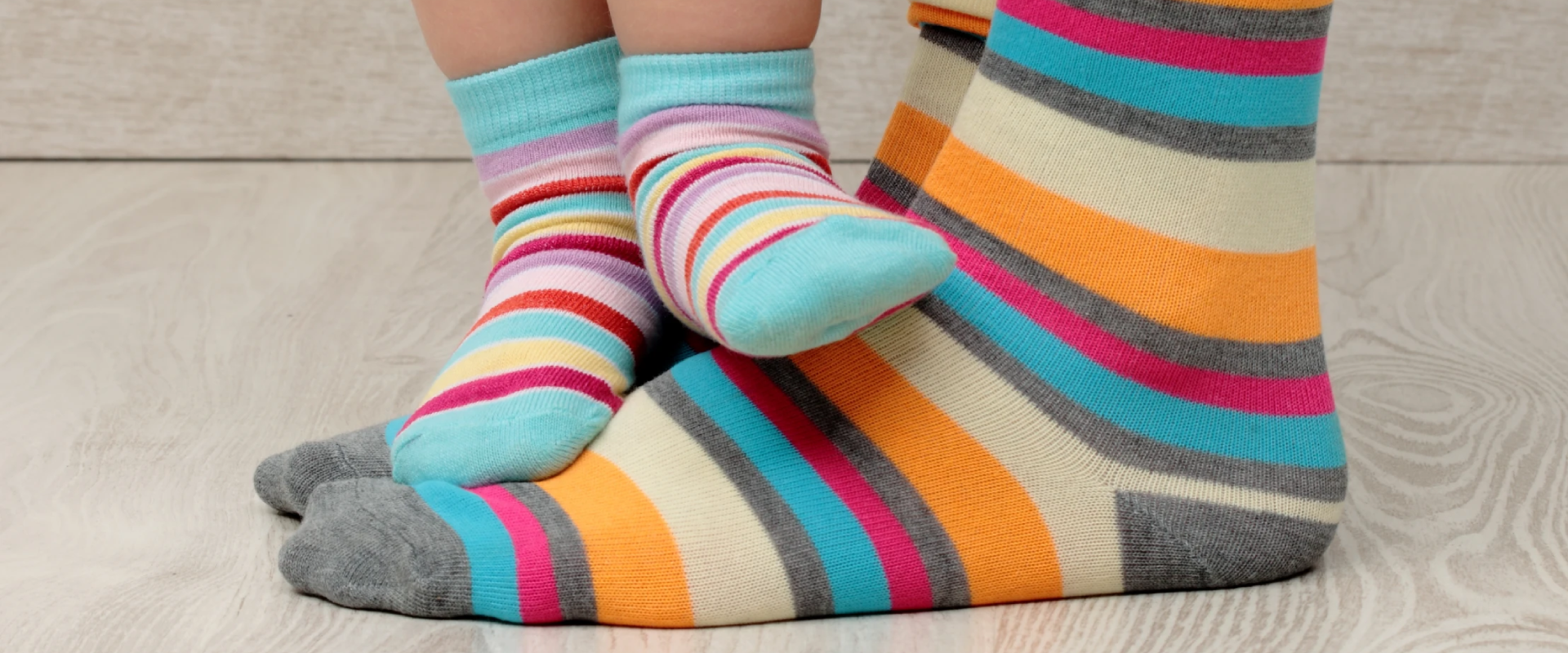 An adult and a child standing toe to toe in matching striped socks